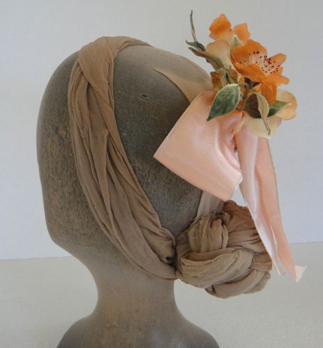 A wide peach ribbon bow forms the base of this headdress.