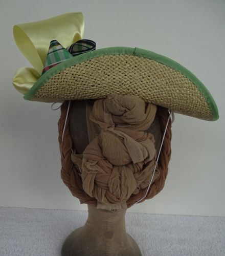 The back of the brim has been turned up to accommodate a large hairstyle.  This hat has a small crown and is meant to sit atop the head.