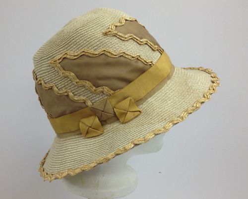 This paper straw hat was made in 2018 and trimmed with large stylized leaves of fabric edged with zigzag straw.