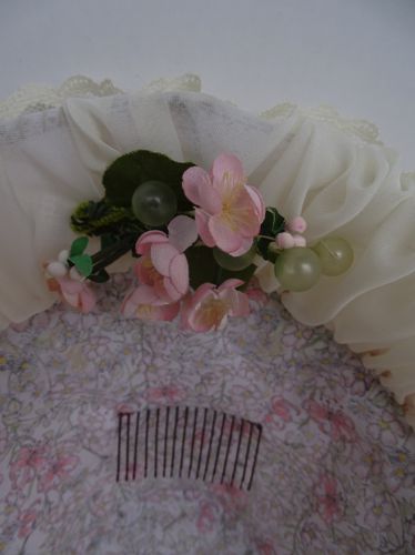 Detailed view of the inner brim shows a small grouping of flowers, and the wire comb which helps keep the bonnet in place on the head.