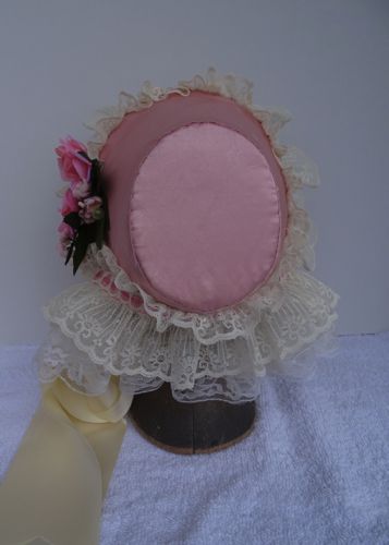 The tip of this bonnet is oval, and it has been covered with a satin of silk/cotton blend.  The curtain is a double frill of lace.