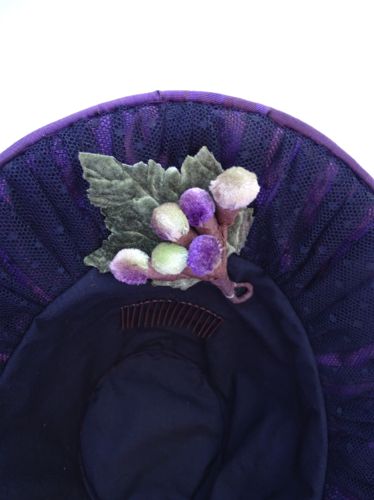 Detailed view of velvet grapes cluster inside brim of bonnet.