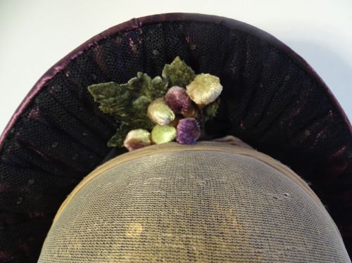 The inner brim is trimmed with gathered black lace, and some of the same grapes found on the outside.