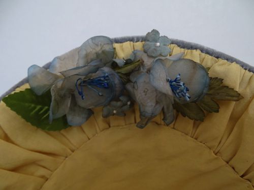The inside of the brim is trimmed with a small grouping of hand-tinted organza flowers in grey/blue.