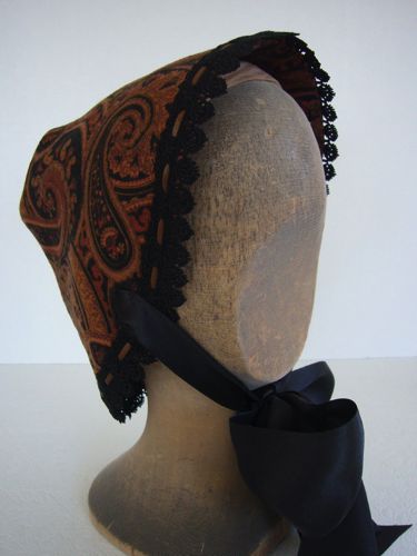 The bonnet has a comb inside to help keep it in place as well as strings made of very wide black satin ribbon.