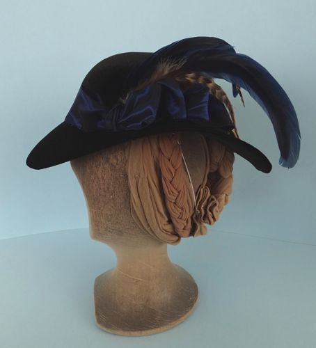 At the left side, and towards the front are a series of blue taffeta bows, behind which are placed several rooster and pheasant feathers in blue and brown.
