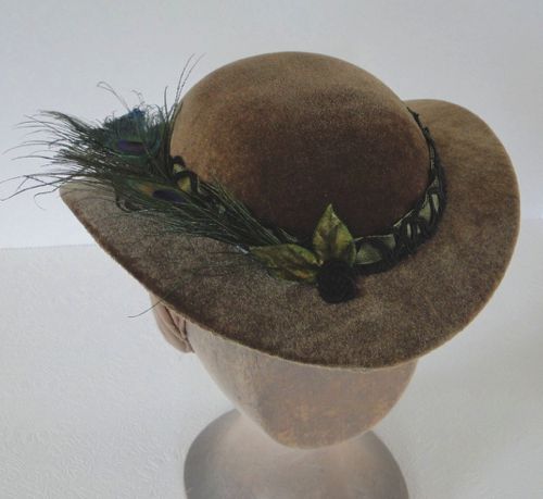 The hat band is made of taffeta ribbon and black gimp, there are leaves and small ribbon roses at the front.