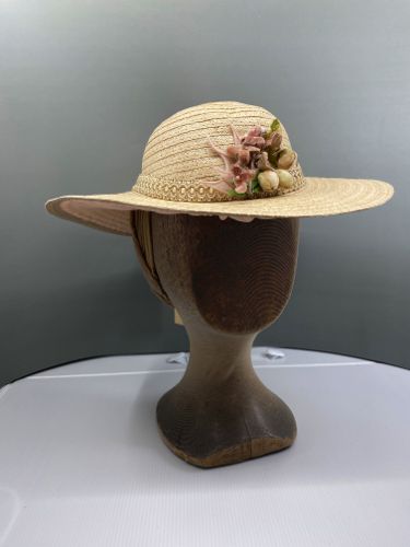 This "gardening" style hat is trimmed simply, with a fancy beige gimp hat band and some neutral colored flowers.
