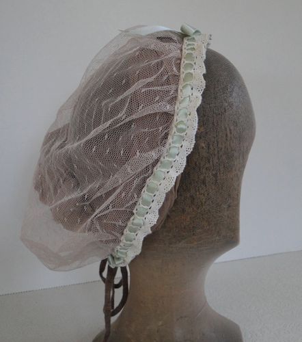 The cap is edged with cotton crochet lace that has been strung with a green satin ribbon.