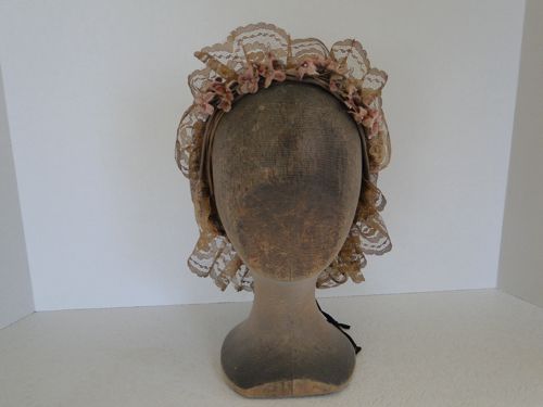 This tan lace cap has a frill which gives height to the front.  This style was popular in 1864.