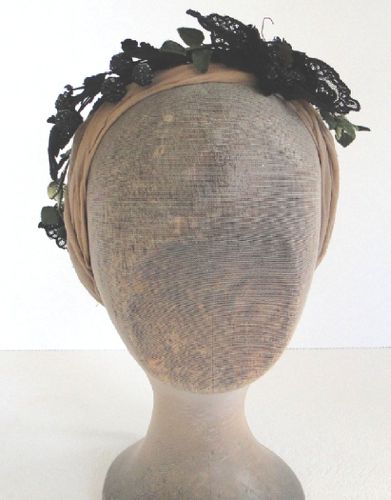 The base was made from ribbon stitched over a circlet of wire.  On it are black ivy leaves, black glass raspberries, black lace motifs and an antique black sequin butterfly.