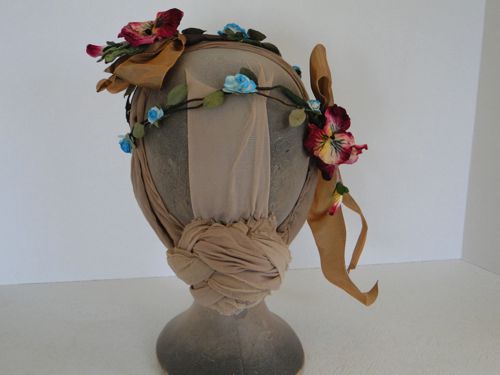 Two sets of wine-red pansies were stitched to the circlet in an asymmetrical arrangement.  Tan ribbons were also added to co-ordinate with the gown.