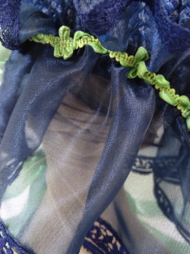 Detailed view of the curtain which is trimmed with a varigated green braid at the header.