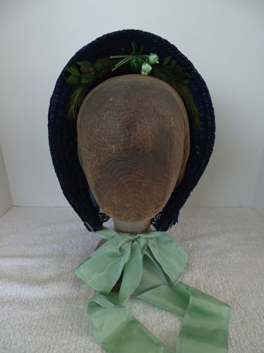 The inside of the brim is trimmed with grasses, leaves and flowers.  Long taffeta ribbons form the ties.