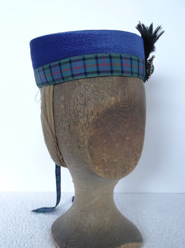 The plaid ribbon co-ordinates with the blue straw, as well as the green in the brooch and the black and red in the feathers.