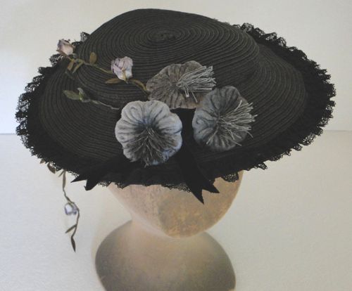 The front is trimmed with three hand tinted grey velvet flowers and a black velvet ribbon bow.