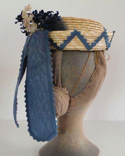 The crown and brim are of straw braid, and the trims are blue ribbons and flowers.