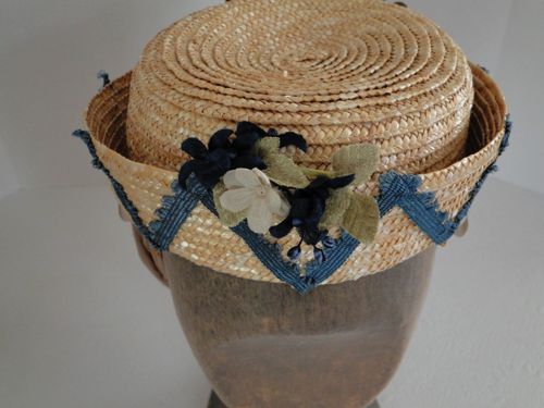 A small bouquet of off-white and navy blue flowers trims the front.