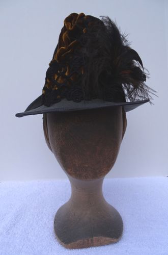 Tall-crowned hat of grey felt trimmed with gold velvet, black lace, and feathers