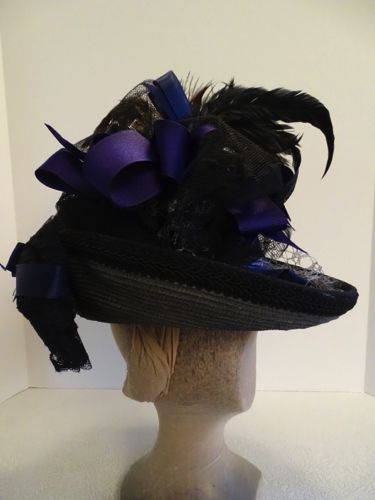 This grey straw hat is exuberantly trimmed with navy and purple ribbons, rooster tail feathers, and crinoline bows.