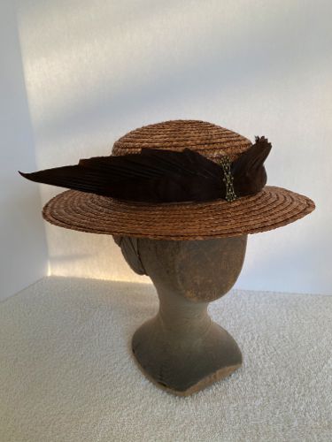 This brown straw boater has been trimmed with satin "folds" and antique pasted wings.