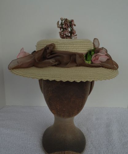 The outer edge of the hat has been trimmed with a straw that has little points sticking out. A sprig of lilacs at the back adds vertical interest.