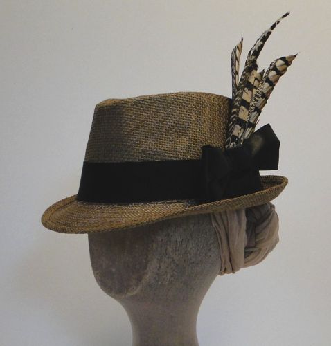 This 1896 sporty-style brown hemp Trilby is trimmed with a black petersham band, black satin ribbon bow, and black and brown pheasant feathers.