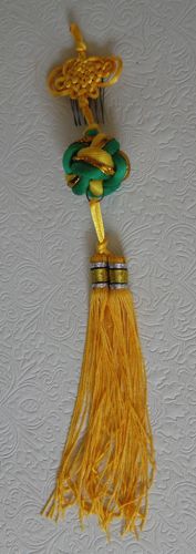 Pin-in hair decoration with gold tassels and green and gold cord knot.