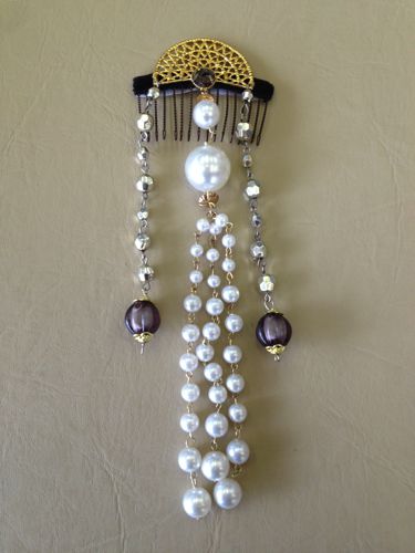 This hair decoration was assembled using various pieces of costume jewelry that were attached to a velvet-covered wire hair comb.